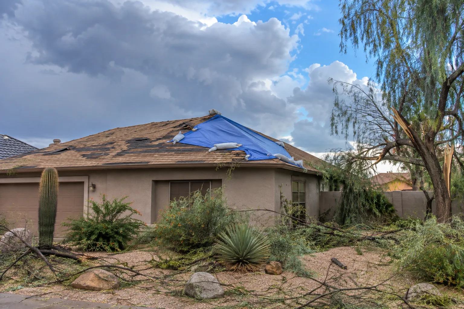 Emergency tarp secured over a monsoon-damaged roof section on an Arizona home